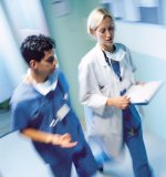 A nurse is walking down a hallway with a doctor.